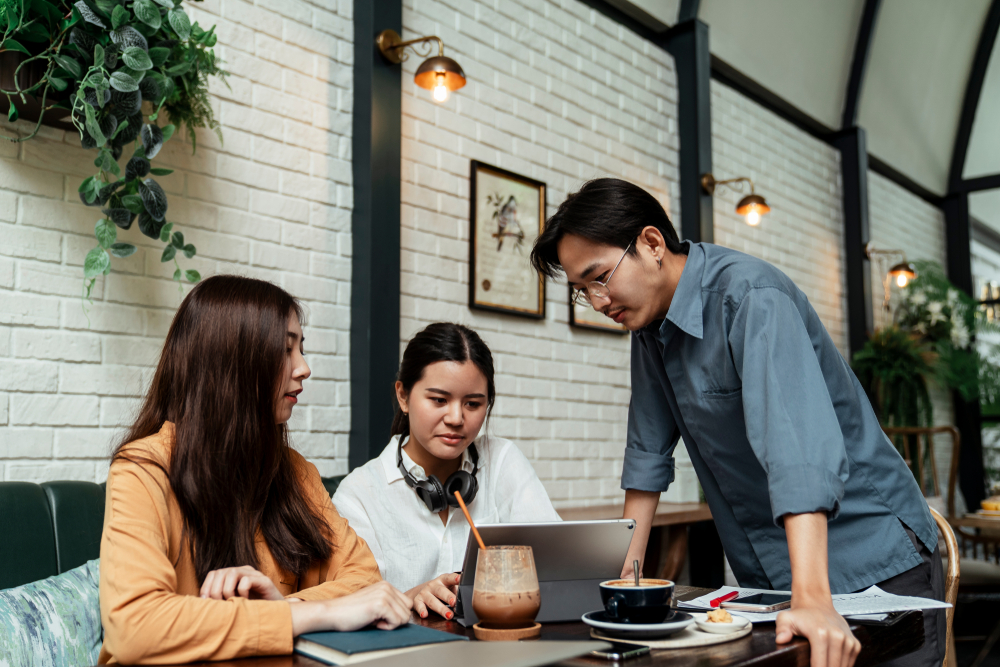 three,colleagues,discussing,business,plan,design,in,cafe.